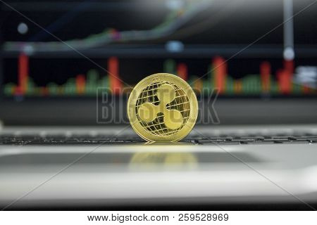 Golden Ripple Coin On A Black Keyboard Of Silver Laptop And Diagram Chart Graph On A Screen As A Bac