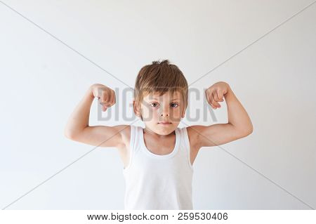 Cute Stong Healthy Caucasian Boy In White Shirt Showing Biceps Muscle On White Background