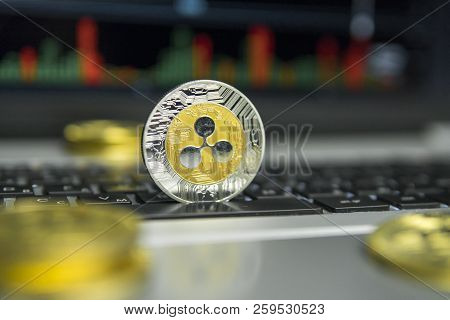Golden And Silver Ripple Coin With Gold Coins Lying Around On A Black Keyboard Of Silver Laptop And 