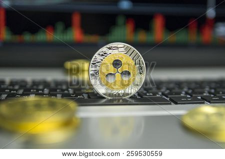 Golden And Silver Ripple Coin With Gold Coins Lying Around On A Black Keyboard Of Silver Laptop And 