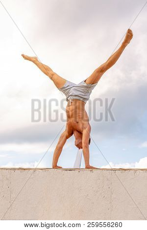 Man Stands On His Hands Against A Beautiful Blue Sky