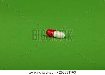 Close Up One Red And White Gel Cap Pill Of Medicine Over Natural Green Background With Copy Space, H