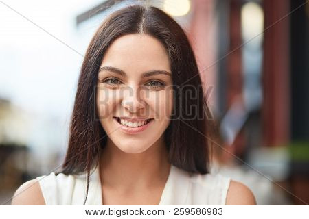Headshot Of Pleasant Looking Charming Smiling Young Woman With Healthy Skin, Dark Hair, Being In Goo