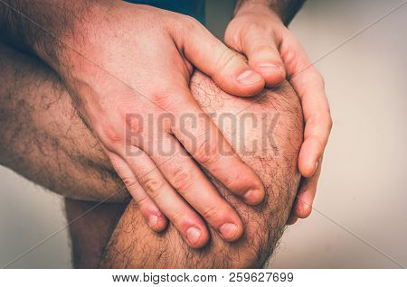 Man With Knee Pain Is Holding His Aching Leg - Body Pain Concept - Retro Style