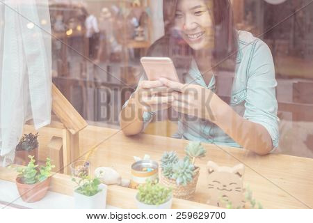 Asian Businesswoman Hand Using The Smart Mobile Phone With Happiness Action On The Desk Beside The G