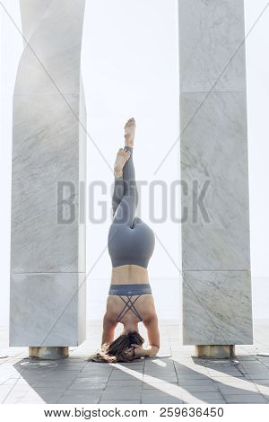Young Woman Doing Complex Yoga Exercise Headstand With City Urban View. Attractive Woman Practicing 