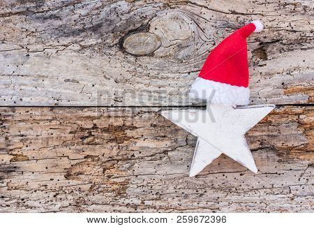 White Christmas Star With Red Santa Hat On Old Wooden Background With Copy Space