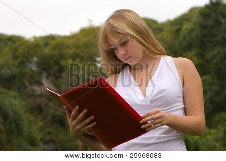 La ragazza sulla natura con un libro di scrittura