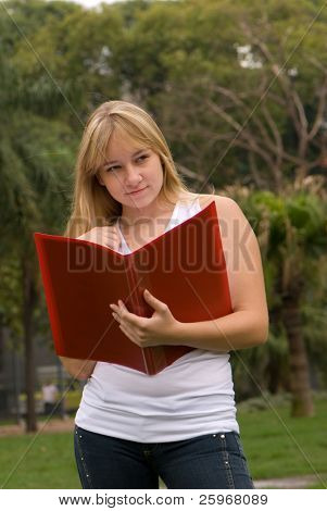 La ragazza sulla natura con un libro di scrittura