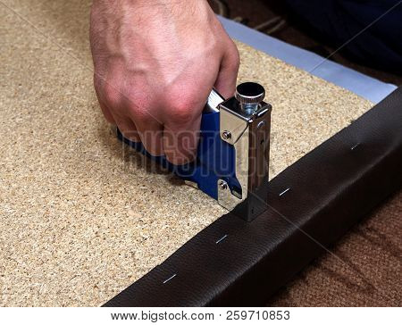 Upholsterer Covering Particle Board With Brown Leather Using Blue Stapler And Staples