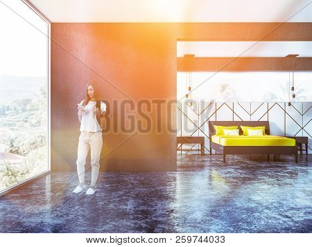Woman In Pajamas Looking At Smartphone Screen Standing In A Black And White Bedroom Interior With A 