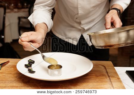 Chef is putting puree to plate using culinary form