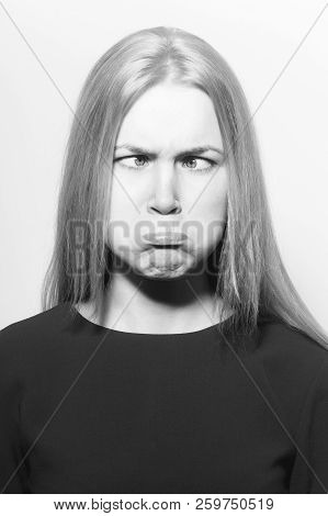 Girl Squinting Eyes And Puffing Cheeks On Funny Face. Young Woman With Crossed Grey Eyes, Healthy Sk