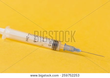 Single Syringe On Yellow Background. Medicine Contep.