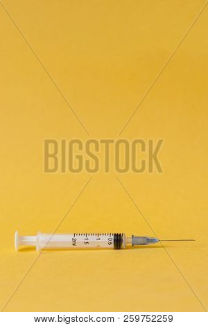 Single Syringe On Yellow Background. Medicine Contep.