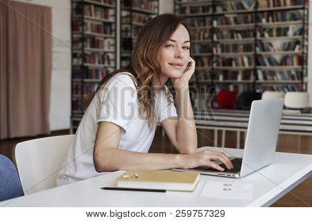 Young Woman Long Hair Analyst Working At Co-working Office On Laptop, Look To Camera, Calm Face, Boo