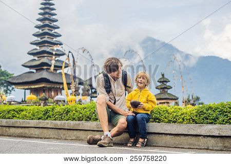 Dad And Son In The Background Of Pura Ulun Danu Bratan, Bali. Hindu Temple Surrounded By Flowers On 