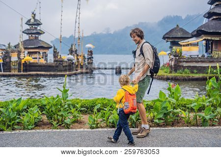 Dad And Son In The Background Of Pura Ulun Danu Bratan, Bali. Hindu Temple Surrounded By Flowers On 
