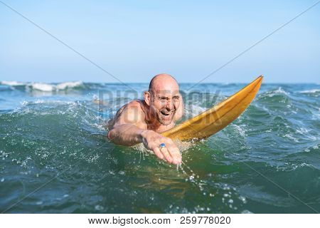 A senior man on a surfboard