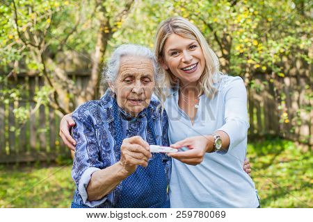 Happy Woman Expecting A Baby, Holding Pregnancy Test, Spending Time With Future Great-grandmother