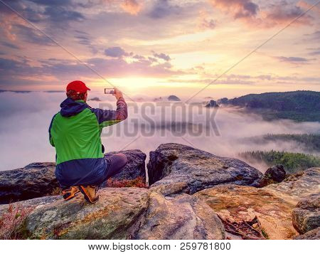 Hiker Takes Selfie Photo, Fall Nature Adventure. Man Sit On Stone On Mountain Sumit  Daybreak Horizo