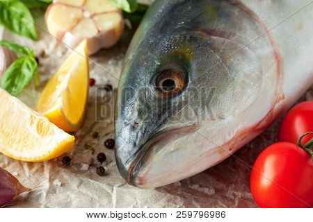 Fresh Tuna Fish Lying On Paper On Wooden Texture With сherry Tomatoes And Herbs