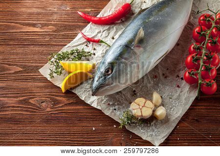 Whole Fresh Tuna With сherry Tomatoes, Lemon, Basil, Garlic And Spices On Baking Paper On Wooden Bac