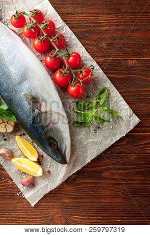 Whole Fresh Tuna With сherry Tomatoes, Lemon, Basil, Garlic And Spices On Baking Paper On Wooden Bac