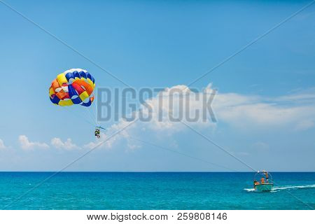 People Flying On A Colorful Parachute Towed By A Motor Boat