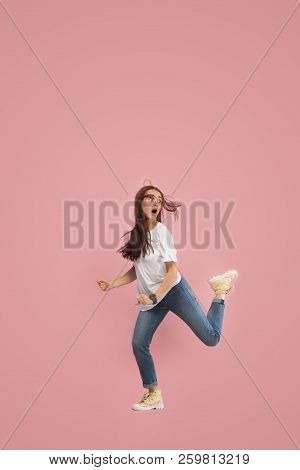 Freedom In Moving. Mid-air Shot Of Pretty Frightened Running Away Young Woman Jumping Against Pink S