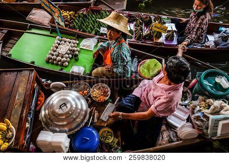 BANGKOK – MARCH 18: People shopping food from wooden boats at Amphawa floating market on March 18, 2