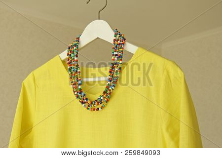 Bright Beads Of Murano Glass Hang On The Background Of A Yellow Summer Dress. Summer Jewelry, Summer