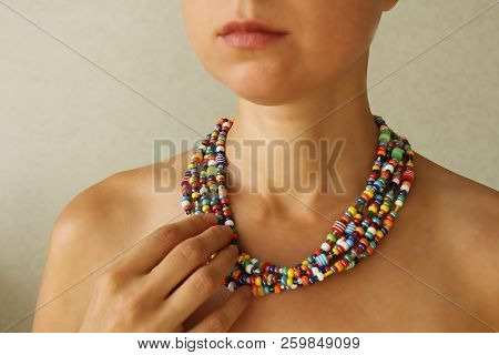 Bright Beads Of Murano Glass On A Young Girl. The Girl's Hand Touches The Beads
