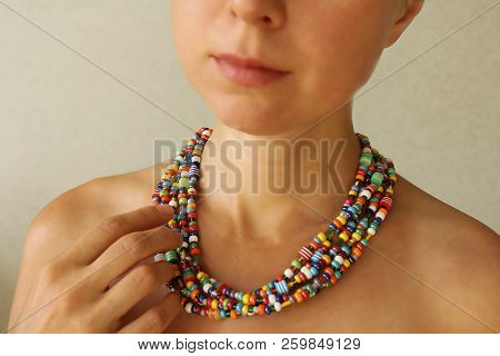 Bright Beads Of Murano Glass On A Young Girl. The Girl's Hand Touches The Beads