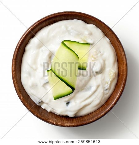 Tzatziki In Brown Rustic Wood Bowl With Cucunber Slice Isolated On White From Above.