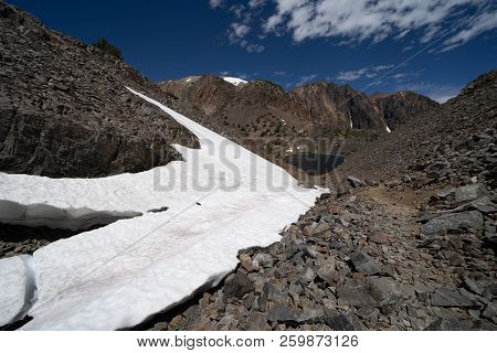 Lots Of Snow Remains On A Trail Of Scree, Talus And Loose Rock Along The 20 Lakes Basin Hike In East