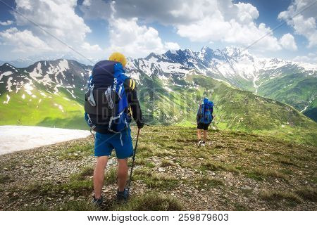 Hiking Trail With Tourists In Mountain Range. Trekking In Mountains. Two Hikers Hike On Snowy Highla