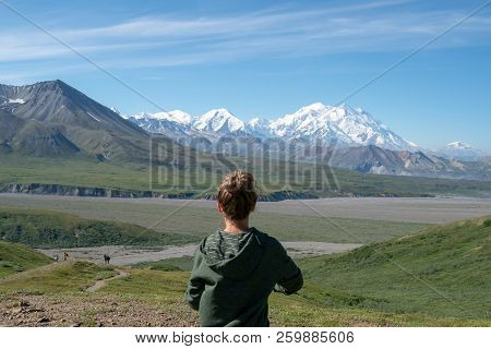 Adult Female Stands In Front Of Denali Mountains In The Alaska Range Of Denali National Park. Concep