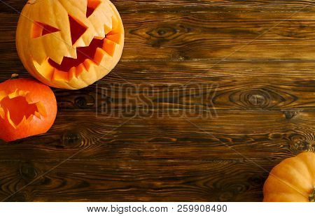 Big Orange Pumpkin Carved Into Jack O Lantern And A Small One In A Shape Of Bat Laying On Wooden Tab