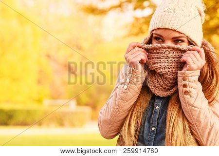 Young Woman Walking In Autumnal Park, Hiding Her Face With Warm Woolen Scarf. Beautiful Sunny Autumn