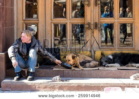 April 15, 2017. Moscow Russia. Arbat Street. Beggar Homeless With Two Dogs Near Shop Front.