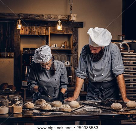 Chef Teaching His Assistant To Bake The Bread In A Bakery.