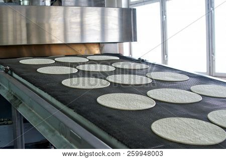 Conveyor with dough, billets for pizza.