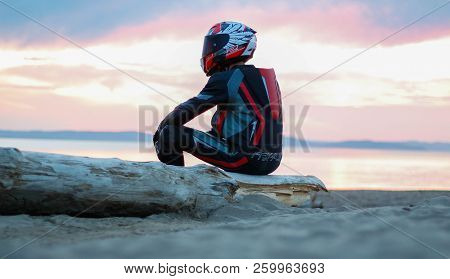 Krasnoyarsk, Russia - August 8, 2018: Motorcyclist In Gear And Helmet Sitting On The Beach By The Se