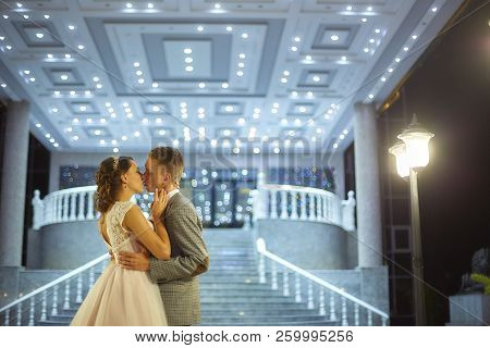 The Bride And Groom Stand On The Beautiful Porch Of The Hotel At Night