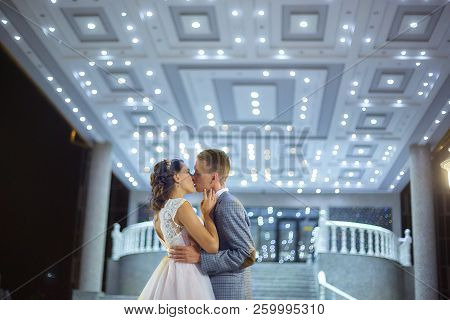 The Bride And Groom Stand On The Beautiful Porch Of The Hotel At Night