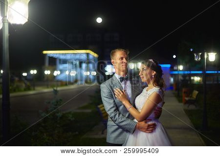 The Bride And Groom Stand On The Beautiful Porch Of The Hotel At Night