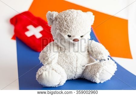 Teddy Bear In A Medical Mask With An Electronic Thermometer In His Pawon