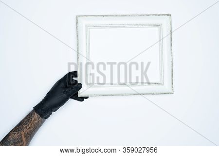 A Man Hand With Black Gloves Holding A Empty(blank) White Photo Frame Isolated On White Background.