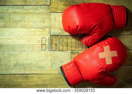 Red Boxing Gloves Placed On Wooden Floor At The Gym. Adhesive Plaster Across Each Other On Boxing Gl